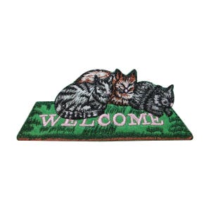 May include: A green welcome mat with the word "WELCOME" embroidered in pink. Three cats are sleeping on the mat, one brown and white, one gray and white, and one black and gray.