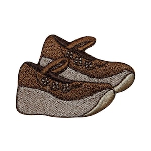 May include: A pair of brown embroidered sneakers with white soles. The sneakers are stitched together and have a lace-up design.