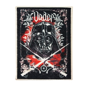 May include: A black and white embroidered patch featuring Darth Vader's helmet with the word "Vader" above it. The patch has a red and black background with a floral design and two crossed lightsabers.