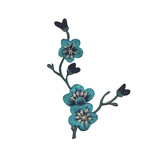 May include: Embroidered blue flower patch with a green stem and navy blue leaves. The flower has a gold center.