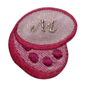 May include: Pink and red embroidered patch with a white oval in the center. The oval has a gold embroidered letter "M" inside. The patch has a pink and red polka dot design around the oval.