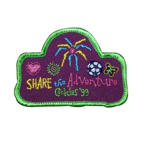 May include: Purple embroidered patch with green stitching. It features a heart, a sun, a football, a butterfly, and fireworks. The text reads "SHARE the Adventure Cookies '99".