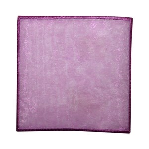 Peut inclure: Un carré de poche lavande en tissu translucide et scintillant. Les bords sont bordés d'une bordure cousue violet foncé. Le carré de poche est posé sur un fond blanc.