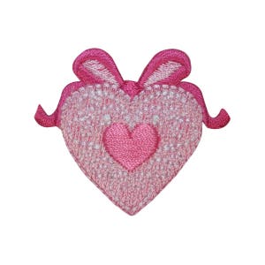 May include: Pink felt heart with a smaller pink heart in the center, surrounded by a white lace design. The heart has two pink felt loops at the top, resembling a bow.