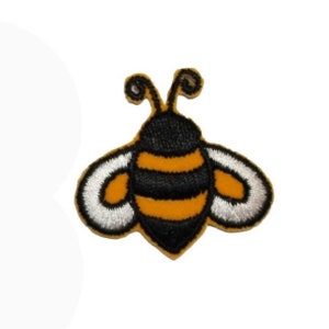 May include: An embroidered bee patch in yellow and black with white wings. The bee is cartoon-style and has a black head and antennae.