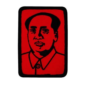 May include: A red embroidered patch with a black outline depicting a portrait of a man with a serious expression. The man is wearing a collared shirt.