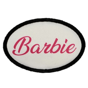 May include: White oval patch with a black border. The word "Barbie" is written in pink cursive letters.