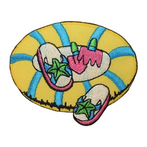 May include: Embroidered patch featuring a yellow inflatable ring with blue stripes. Two pairs of flip-flops with pink straps and green starfish designs are on the ring. A pink and green ice cream cone is also on the ring.