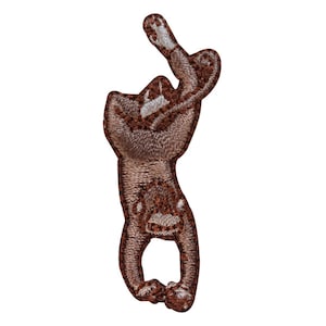 May include: A brown embroidered patch of a monkey hanging upside down with its arms raised above its head.
