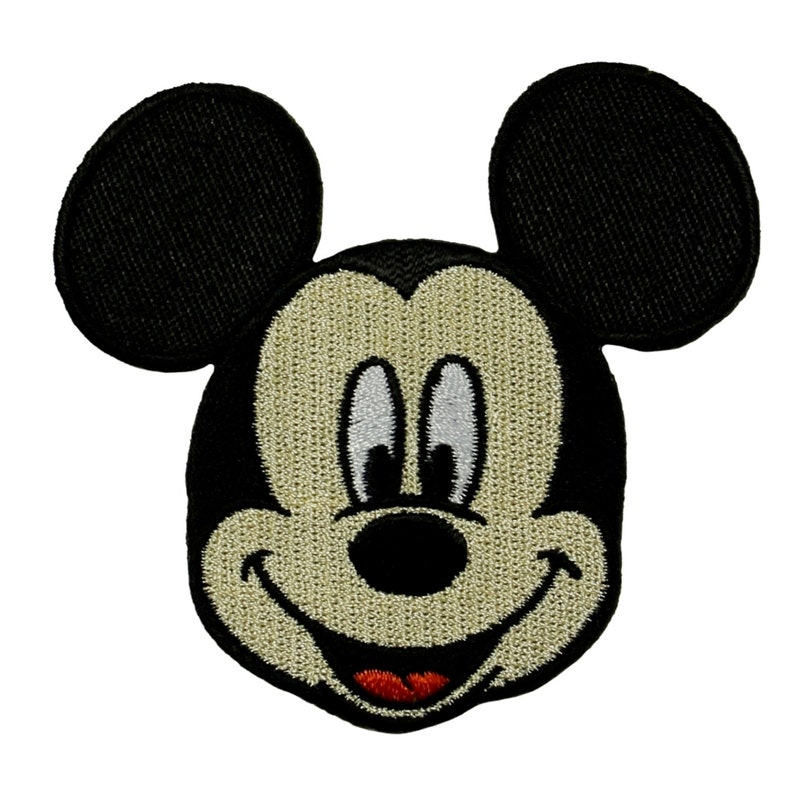 May include: An embroidered patch of Mickey Mouse's face with big black ears and a wide smile, in black and tan.