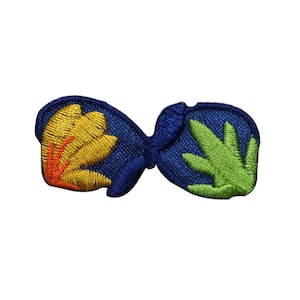 May include: A blue fabric patch with a yellow and orange flower design on one side and a green leaf design on the other side.