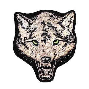 May include: Embroidered patch of a wolf's head with a black background, green eyes, and a snarling expression.