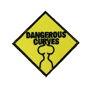 May include: A yellow embroidered patch with a black border and the words "DANGEROUS CURVES" in black block letters. Below the text is a black outline of a curvy figure. The patch is diamond-shaped.
