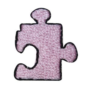 May include: A pink jigsaw piece with a black outline. The piece is made of fabric and has a textured surface.