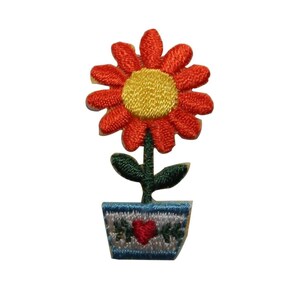 Könnte beinhalten: Eine gestickte Blume mit roten und gelben Blütenblättern in einem blauen und weißen Topf mit einem roten Herzen. Der Topf hat grüne Blätter und Ranken.