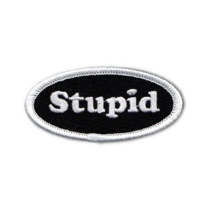 May include: White embroidered text that reads "Stupid" on a black oval patch with a white border.