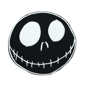 May include: Black and white embroidered patch of Jack Skellington's face from the movie The Nightmare Before Christmas. The patch features his signature stitched smile and large, round eyes.