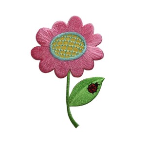 Può includere: Un fiore rosa con un centro giallo e una foglia verde con una coccinella rossa. Il fiore è ricamato e ha uno stelo.