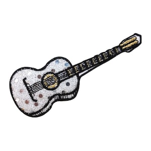 May include: A white acoustic guitar with black and gold details. The guitar is decorated with silver sequins.