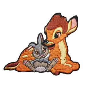May include: Embroidered patch featuring Bambi the fawn and Thumper the rabbit from Disney's Bambi. Bambi is brown with a white belly and Thumper is gray with a pink nose. The patch is perfect for adding a touch of Disney magic to your projects.