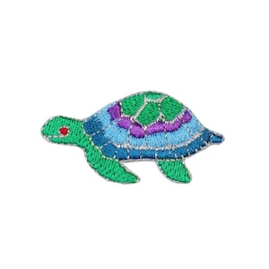 May include: A colorful embroidered patch of a sea turtle with a green shell, blue and purple stripes, and a red eye.