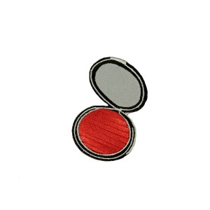 May include: A red blush compact with a black rim and a silver lid. The lid is open and the blush is visible.