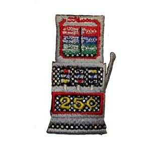May include: A silver and red embroidered iron-on patch of a slot machine with a 25¢ sign. The slot machine has three windows with colorful symbols and a lever.