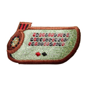 May include: A brown felt patch with a green felt center depicting a roulette wheel with red and black numbers. The patch has a brown felt border.