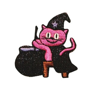 May include: Pink cat wearing a black witch hat and holding a black cauldron. The cat has a star on its hat and is smiling.