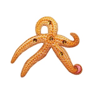 May include: A gold starfish with a pink center, decorated with rhinestones. The starfish is a popular nautical theme for home decor and crafts.
