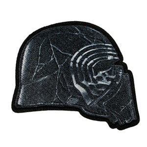 May include: Black and white embroidered patch of a Star Wars character's helmet. The helmet is detailed with cracks and lines.