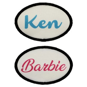 Könnte beinhalten: Zwei weiße ovale Patches mit schwarzen Rändern. Der obere Patch hat das Wort "Ken" in blauer Schrift. Der untere Patch hat das Wort "Barbie" in rosa Schrift.