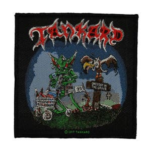 May include: Black woven patch with the band name "TANKARD" in red lettering. The patch features a green cartoon creature pushing a shopping cart with a skull and crossbones on it. A sign reads "One Foot in the Grave". The patch is copyrighted 2017 TANKARD.