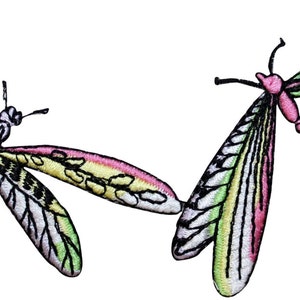 May include: Two colorful embroidered dragonfly patches with pink, green, and yellow accents. The dragonflies are in flight with their wings spread out.