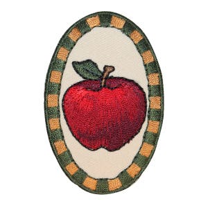 May include: Embroidered red apple with green leaves in a gold and green oval frame.