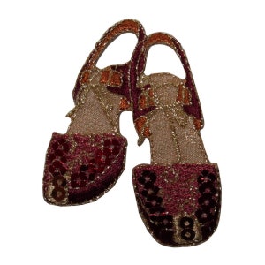 May include: A pair of red and gold sequined shoes with a brown strap and buckle. The shoes are embroidered with gold thread and have a sparkly finish.