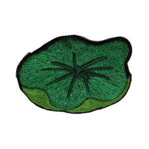 May include: Embroidered patch featuring a green lily pad design with a dark green center and a black border. The patch has a textured appearance, with detailed stitching creating the leaf's veins and shape.