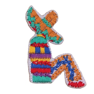May include: A colorful embroidered patch depicting a person wearing a sombrero and sitting with their legs crossed. The patch is made of various colors of thread, including red, blue, yellow, green, and orange.