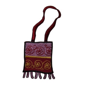 May include: A purple and red embroidered patch with a loop for hanging. The patch features a design of stylized flowers and swirls.