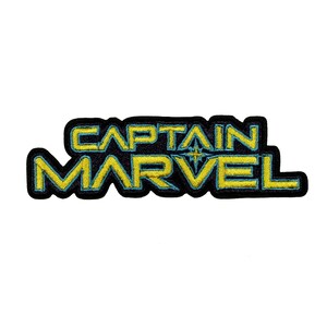 Peut inclure: Un écusson brodé noir et jaune avec le texte "CAPTAIN MARVEL" dans une police de caractères stylisée.