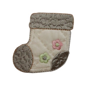 May include: A small, white stocking with a brown embroidered cuff and two embroidered flowers in pink, green, and white.