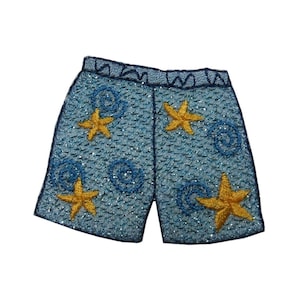 May include: Blue and yellow embroidered iron-on patch of a pair of shorts with a seashell pattern and starfish.