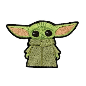 May include: Green embroidered patch of a character from the Star Wars franchise, known as "The Child" or "Baby Yoda". The character is wearing a brown robe and has large eyes.