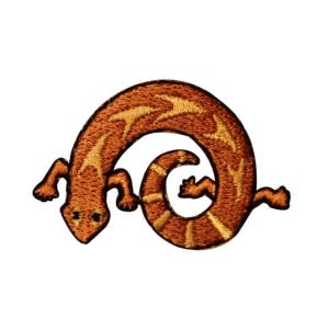May include: An embroidered patch of a curled up brown lizard with yellow stripes.