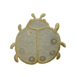 Peut inclure: Un écusson décoratif en forme de coccinelle, avec un corps crème et un contour doré. La coccinelle a six paillettes transparentes sur ses ailes et est faite d'un tissu scintillant. Le patch est conçu pour être cousu ou repassé sur des vêtements ou des accessoires.
