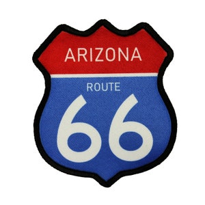 May include: A blue and red Route 66 sign with black stitching around the edges. The sign says "Arizona Route 66" in white text.