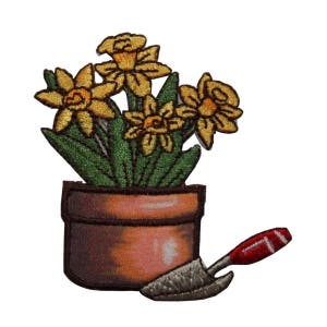 May include: Embroidered patch of a potted plant with yellow daffodils and a small gardening trowel. The pot is brown and the trowel has a red handle.