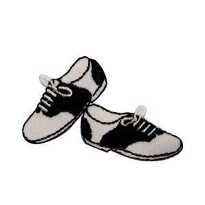 May include: A pair of black and white saddle shoes with white laces. The shoes are embroidered and have a classic design.