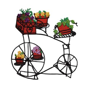 May include: Black metal bicycle-shaped planter with red flower pots filled with colorful embroidered flowers. The bicycle has two wheels and a basket in the front, with additional pots on the frame. The flowers are purple, yellow, and green.