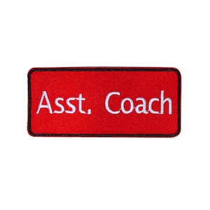 Könnte beinhalten: Roter rechteckiger Patch mit schwarzen Nähten an den Rändern. Der Patch sagt "Asst. Coach" in weißer Stickerei.